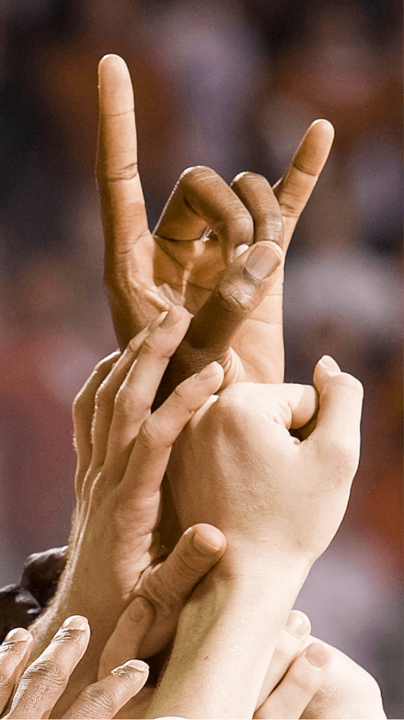 Student hands joining together in the Hook 'Em hand sign.